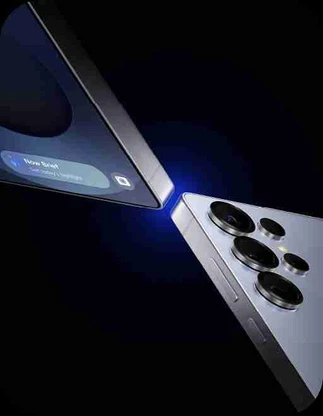 Divi mobilie telefoni (Samsung Galaxy S25) saskaras ar stūriem, zils gaismas stars starp tiem, tumšs fons.