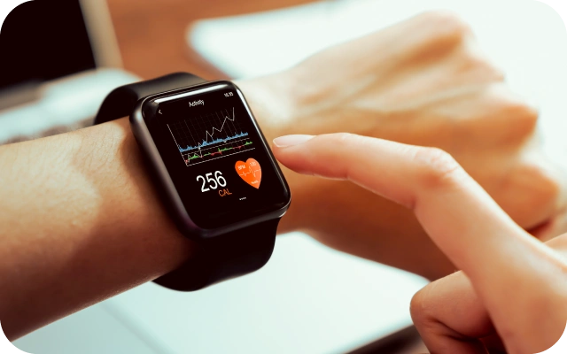 Tuvplāns ar viedpulksteni uz cilvēka rokas, kas rāda sirdsdarbības grafiku un sadedzinātās kalorijas.