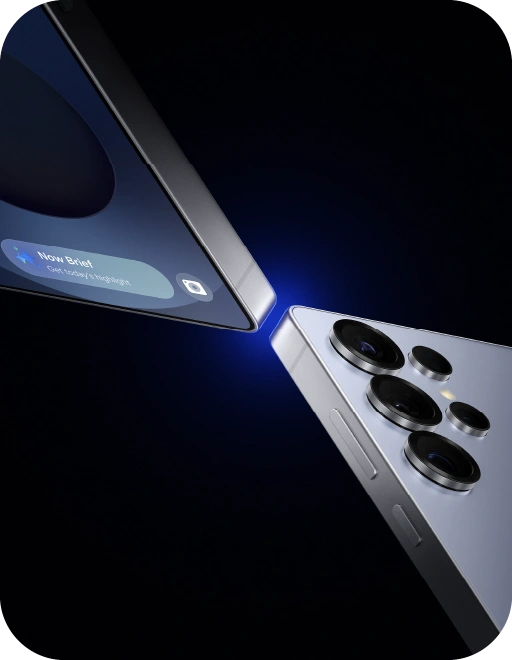 Divi mobilie telefoni (Samsung Galaxy S25) saskaras ar stūriem, zils gaismas stars starp tiem, tumšs fons.