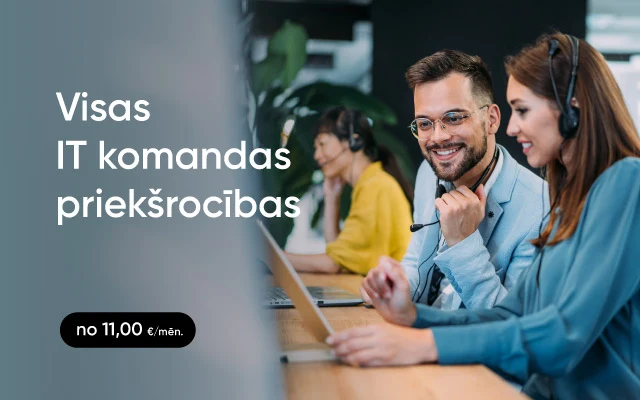 Vīrietis un sieviete sēž pie biroja galda viens otram blakus un skatās sievietes portatīvā datora ekrānā; abiem ir austiņas ar mikrofonu, fonā citi kolēģi darbojas.